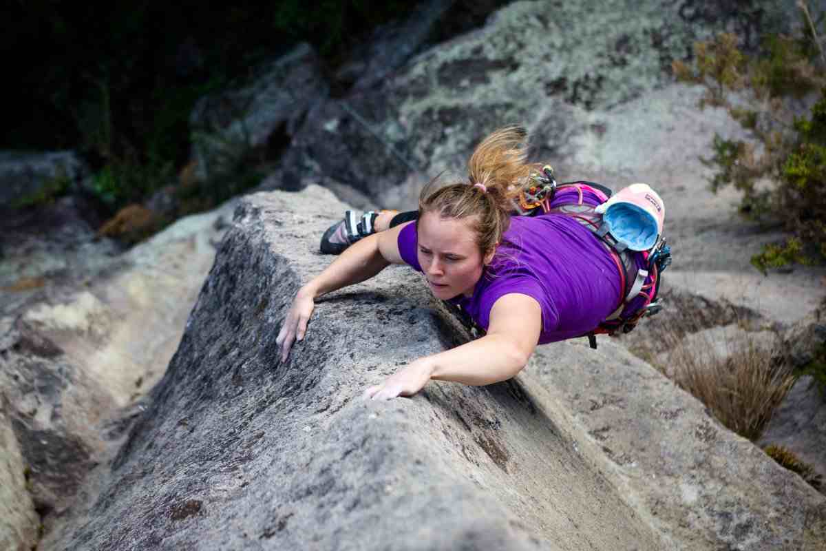 Female climber in purple shirt laybacks on rock Crete photographed from above