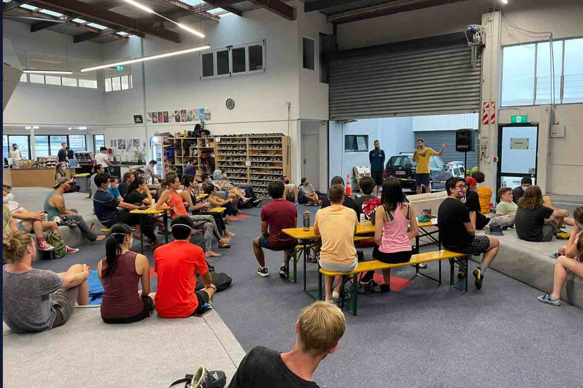 Seated climbers watch a presenter at an indoor seminar.