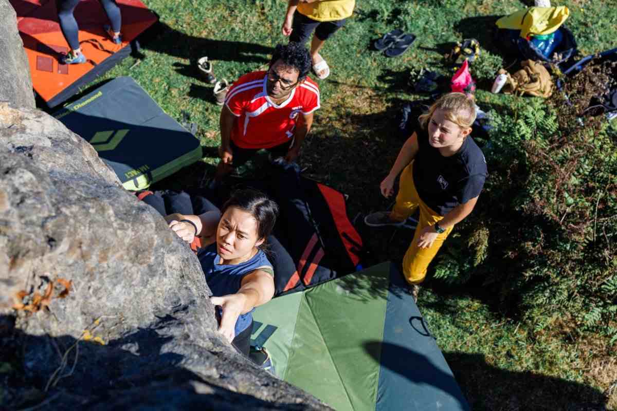 Rock climbers and boulder pads seen from above.