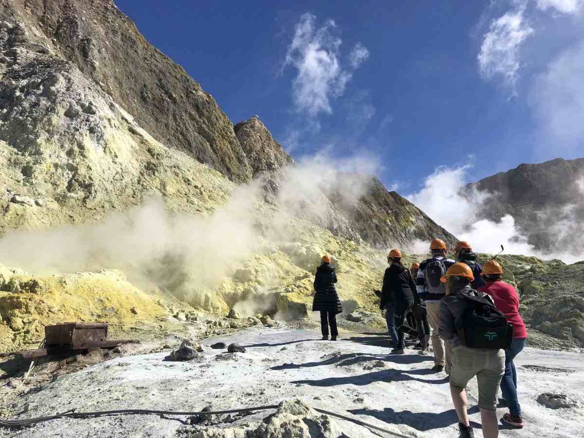 A group of tourists in adventure clothing walking through a volcanic landscape