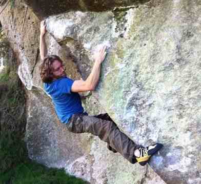 Climber with blue shirt climbing on boulder