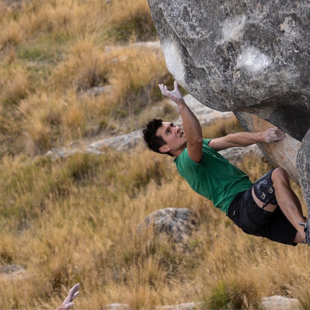 Climber in green shirt bouldering at Castle Hill.