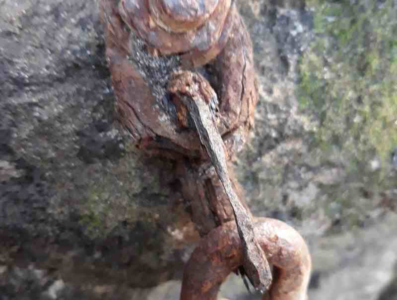 Badly rusted rock bolt and chain links.
