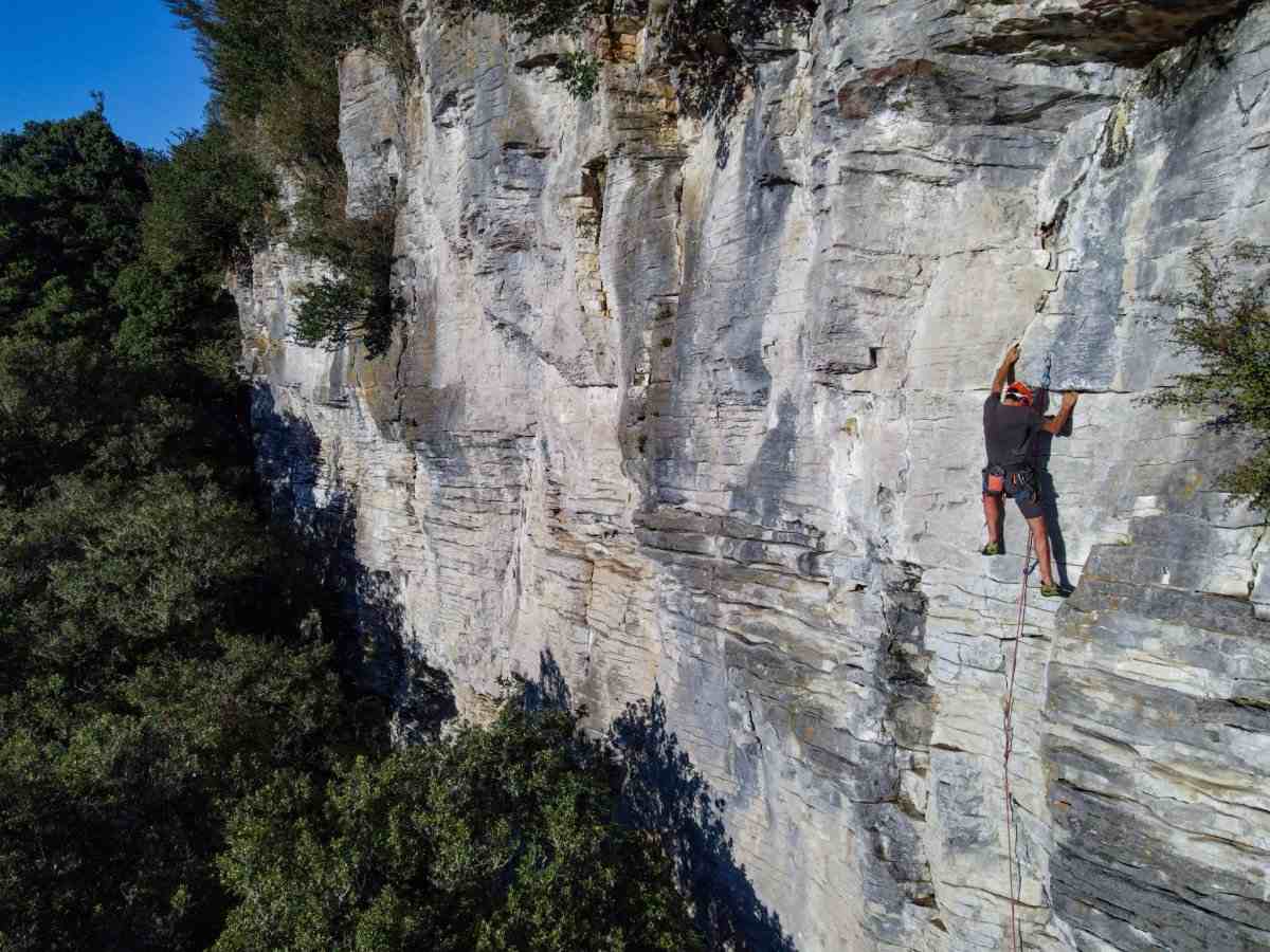 Climber on a limestone cliff above native bush at Pakeho crag