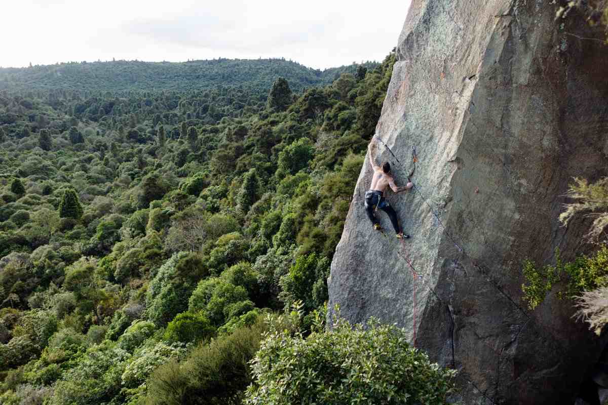 Photo of climber on grey rock with forest below