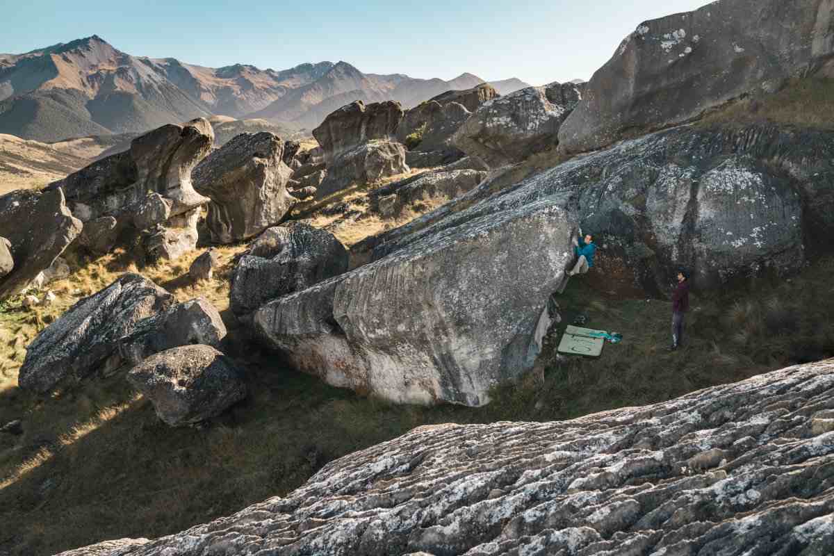 Climber in blue on a grey boulder in a boulder field  