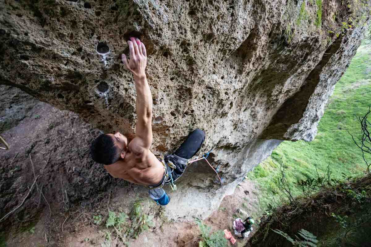 Shirtless climber on steeply overhung pocketed rock in Waikato New Zealand