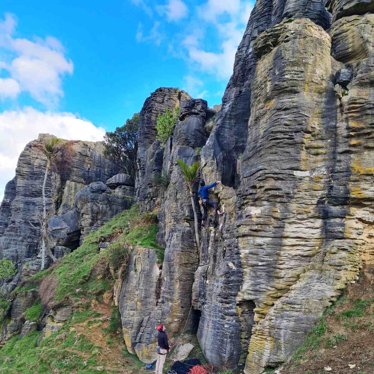 A pair of climbers on a limestone formation with strong horizontal layering.