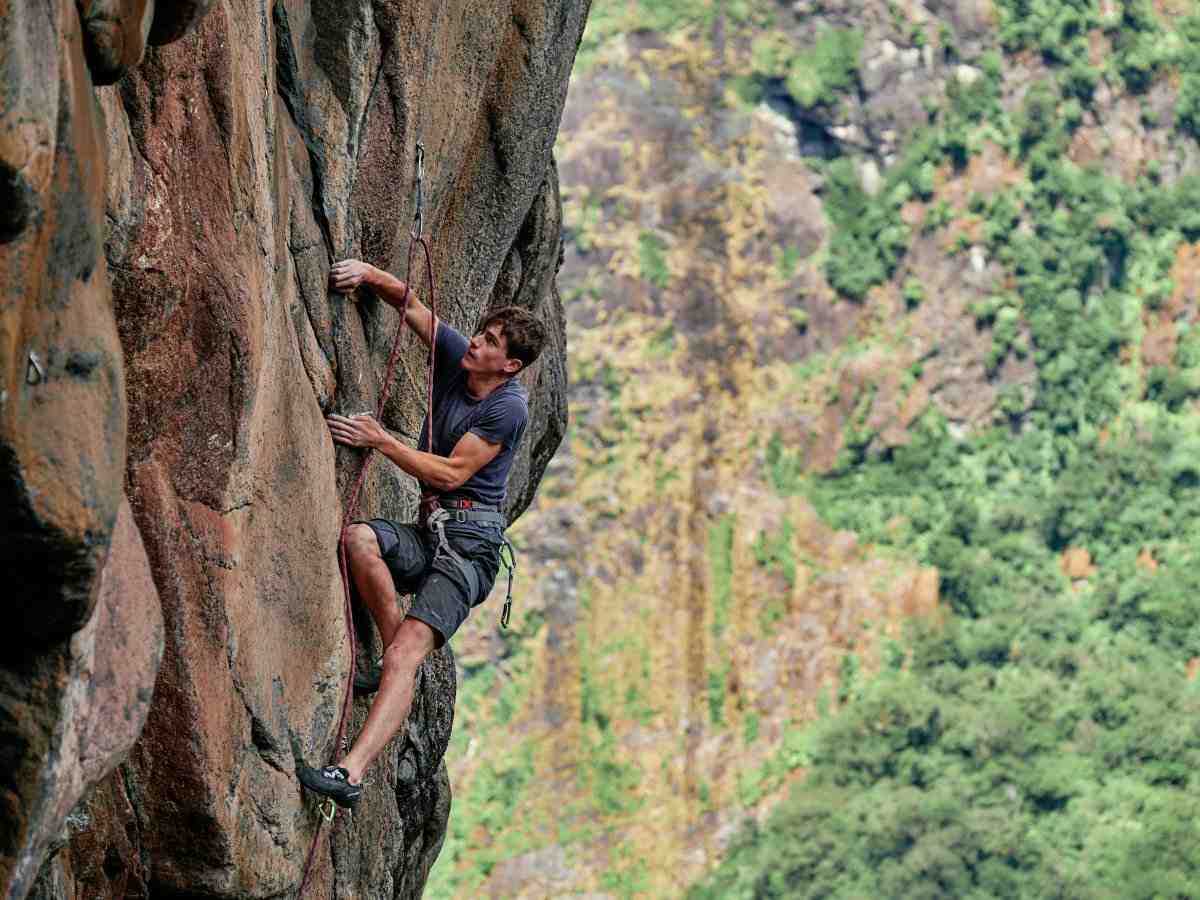 Climber on brown rock with forest in background