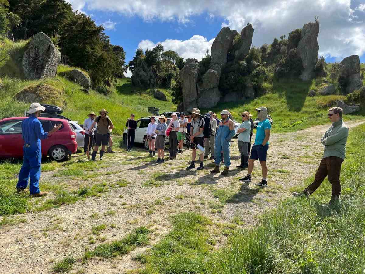 Group of people in car park on farm road with cliffs in background