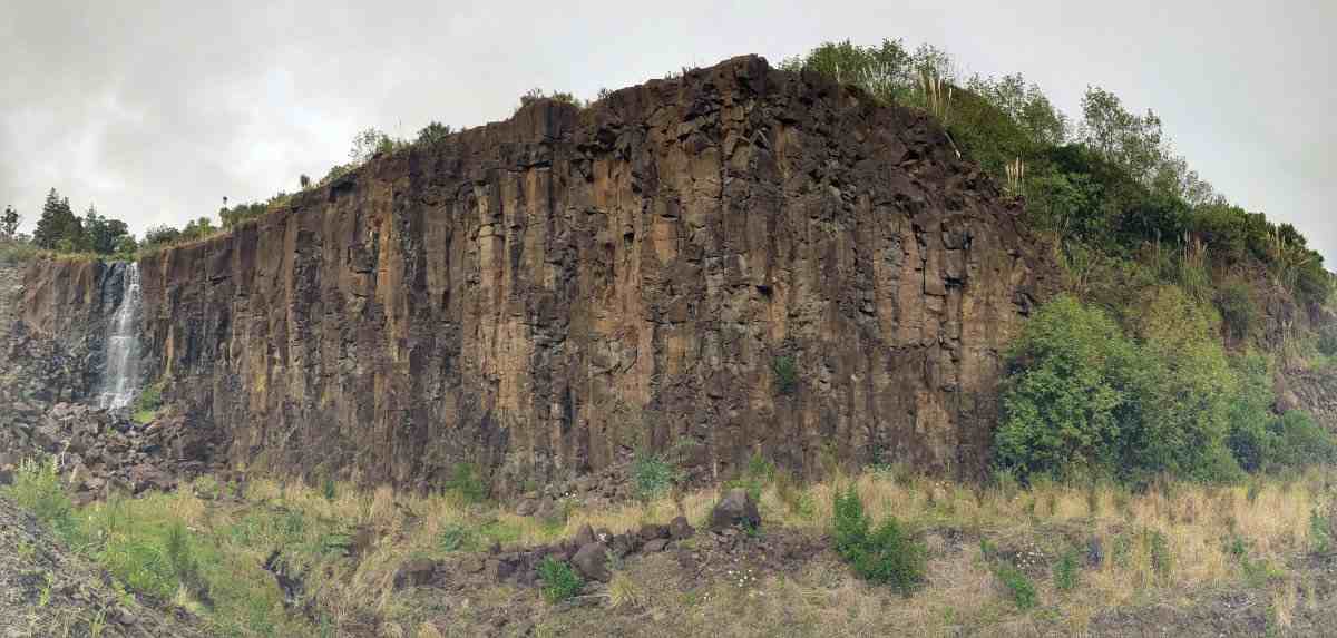 Line of old basalt quarry cliffs with a waterfall at left