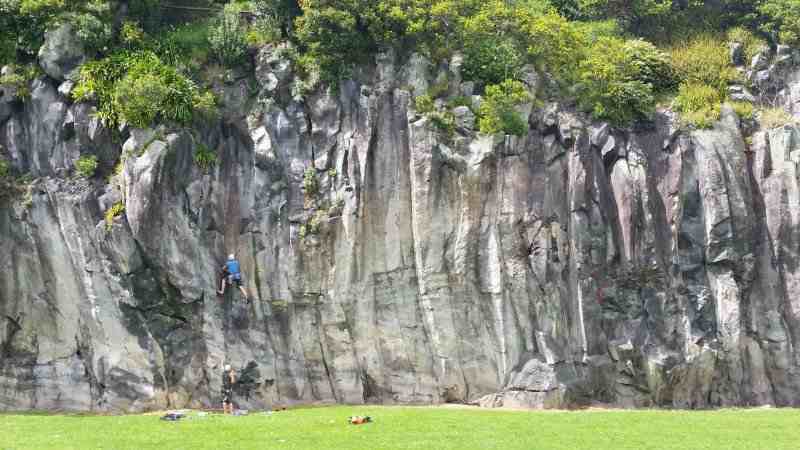 Mt Eden quarry columnar basalt cliff from a distance with 2 climbers