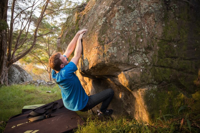Climber in blue shirt bouldering at Wairere Boulders